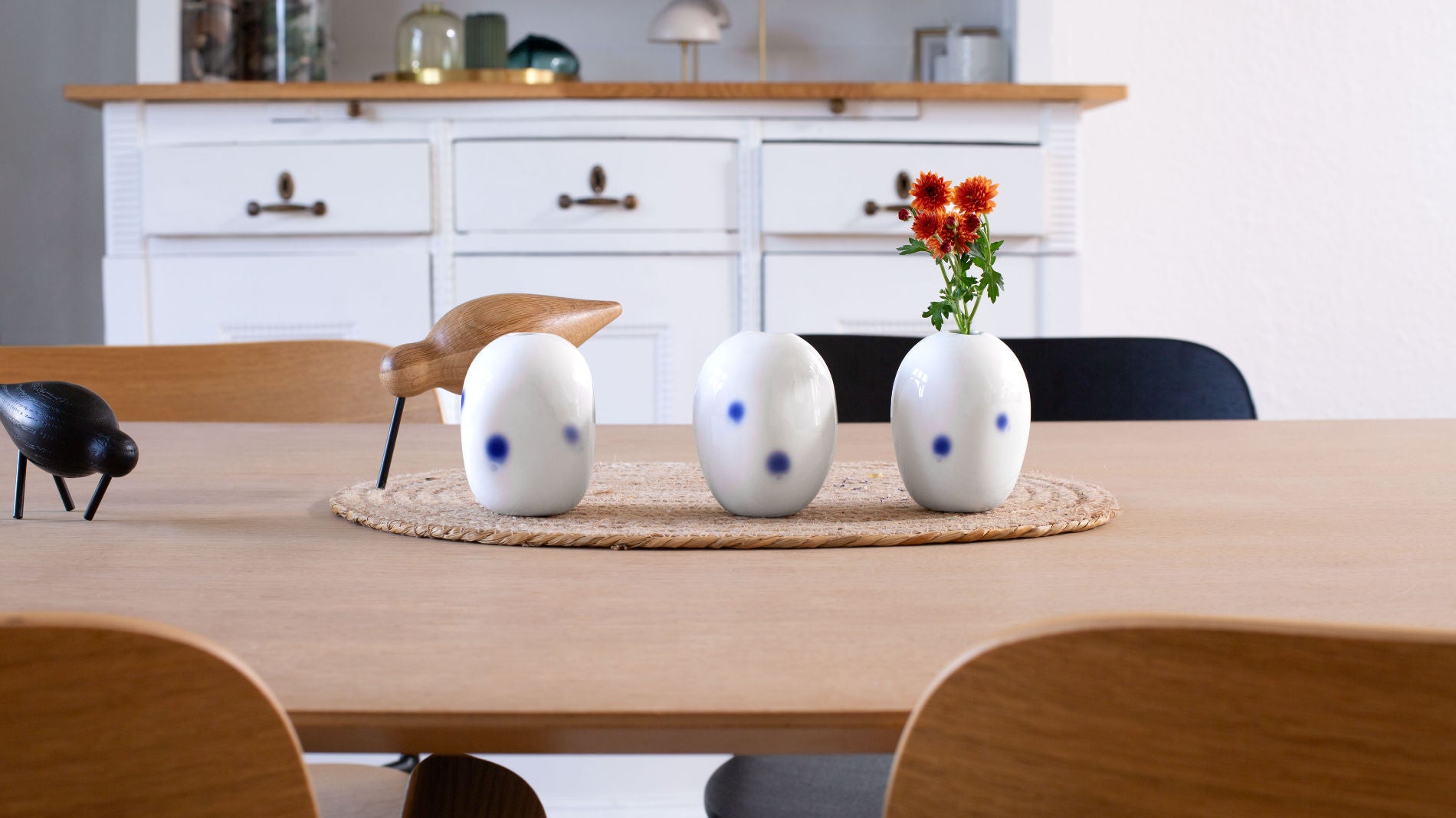 Kleine Blumenvase mit blauen Tupfen arrangiert auf einer großen Tafel. Handmade in Berlin von Katy Jung.