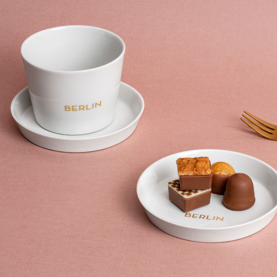 Porzellanbecher Berlin. Ein Schönes Souvenir und Hauptstadtgeschenk mit goldenem Schriftzug. Elegant, mit einem Hauch von Mondänität und Extravaganz. Auch im Set mit kleinem Teller als Geschenk.