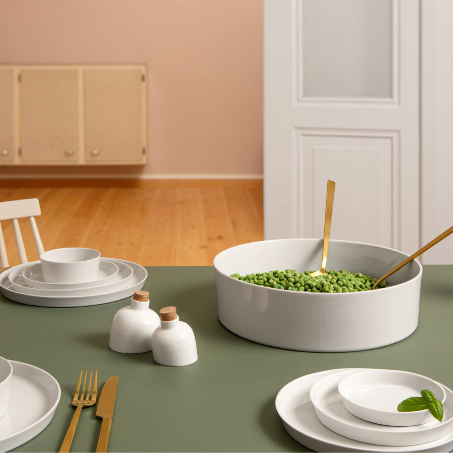 Weißes Porzellangeschirr, Tellerschalenstreuer auf einer gedeckten Tafel.